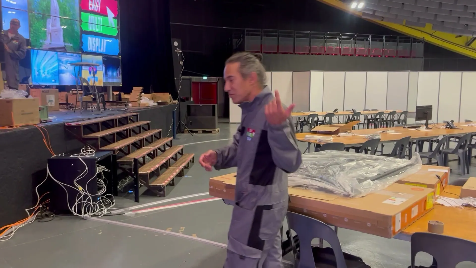 La halle côté tables pendant le montage, les murs d'images en fond, un membre de l'équipe au premier plan