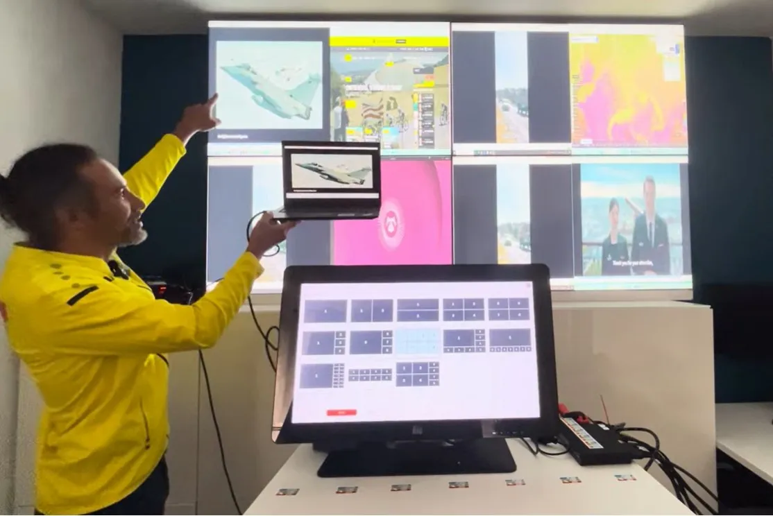 Eight sources shown on a four-screen video wall, driven from the touchscreen standing in front of the wall