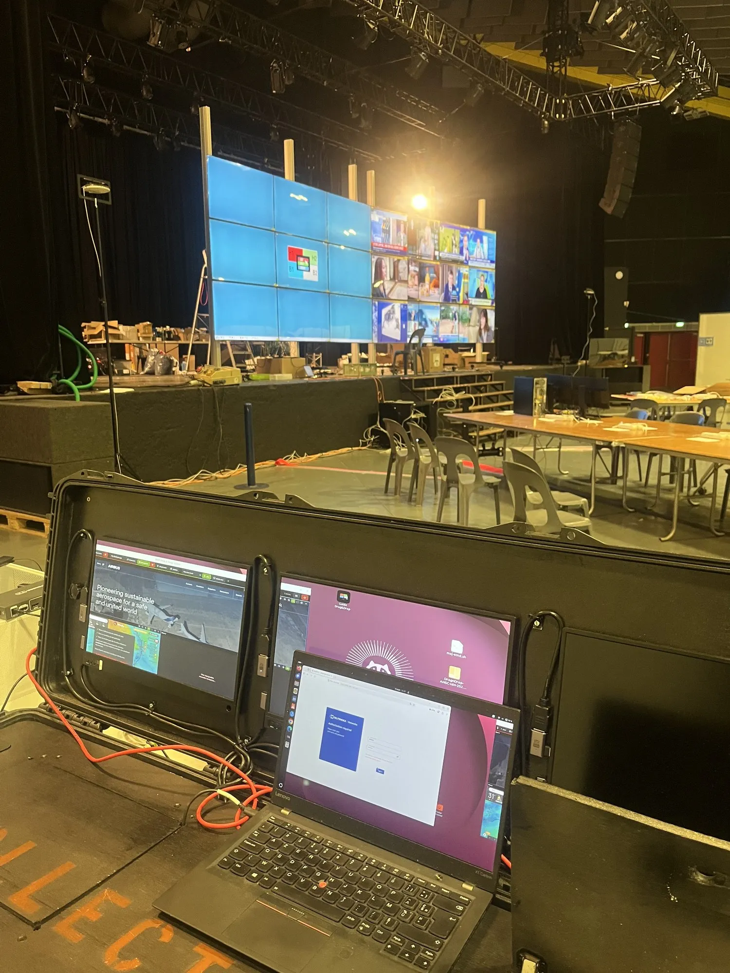 La valigia aperta ai piedi del palco, i due muri video accesi dietro