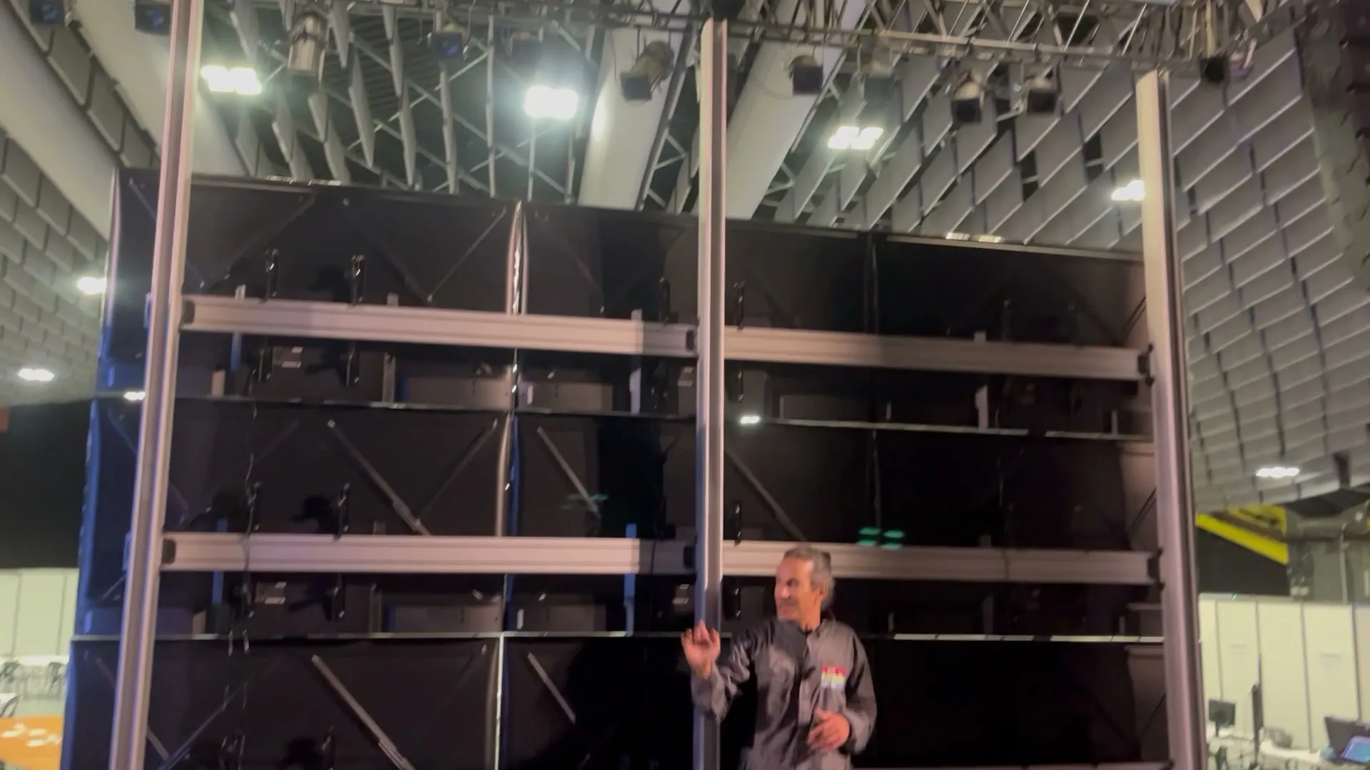 Arrière d'un mur d'images : la structure en aluminium sur toute sa hauteur, un membre de l'équipe à son pied