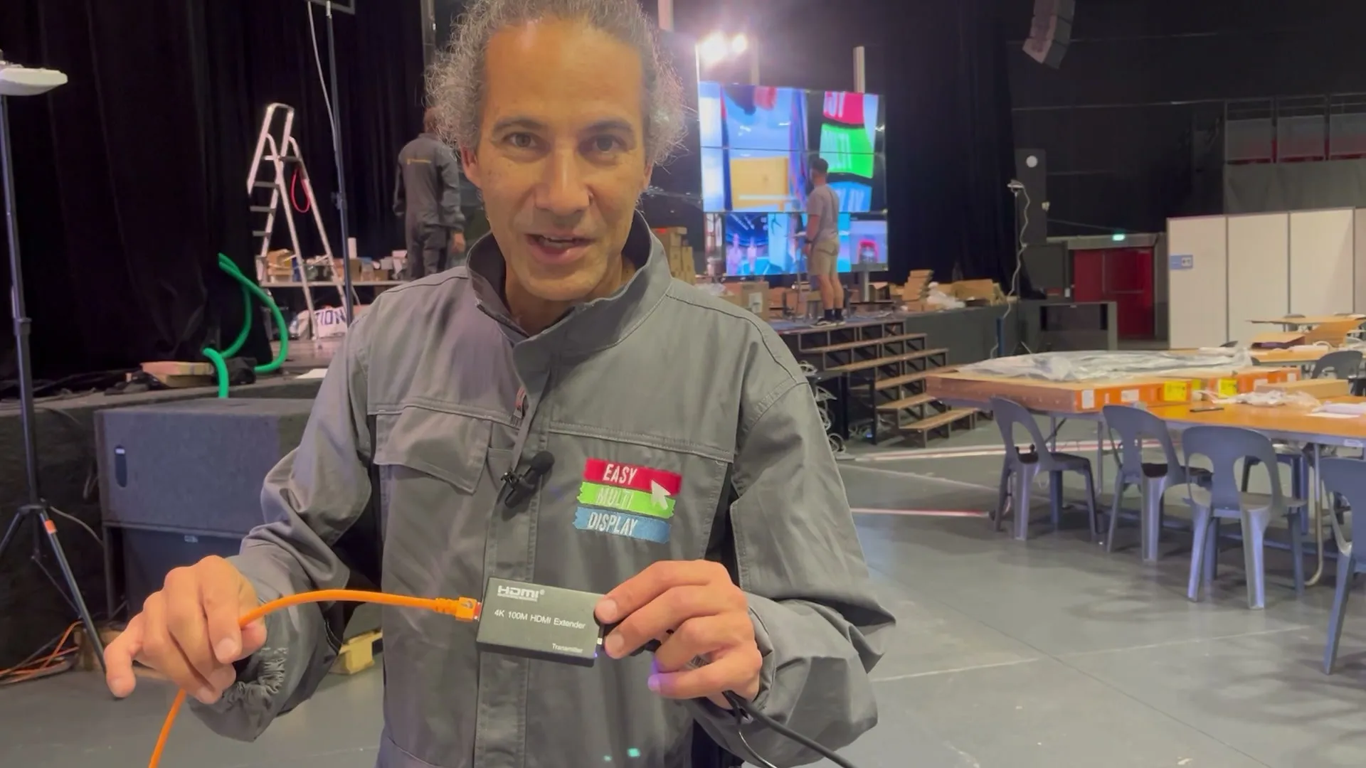 Un membre de l'équipe présente un transmetteur HDMI et son câble réseau orange