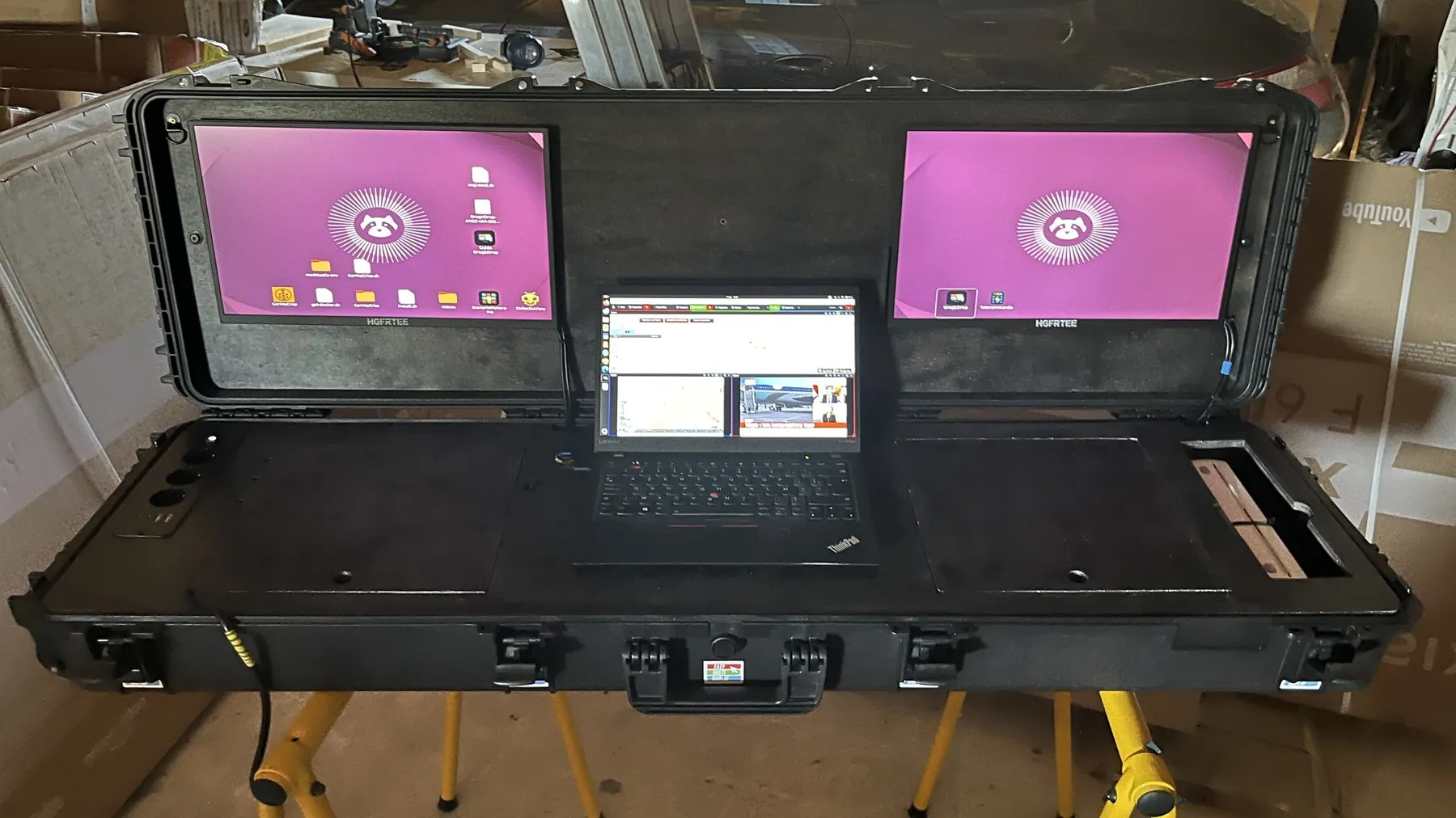 Command case open: two screens lit in the lid and the laptop set in the centre