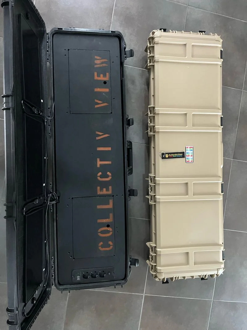 Deux valises tactiques posées au sol : à gauche, une version noire ouverte, marquée CollectivView, avec les emplacements des écrans ; à droite, le prototype v4 fermé, beige sable